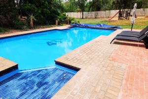 uma piscina com água azul e um pátio em KwaMagogo Villa, Chartwell em Joanesburgo