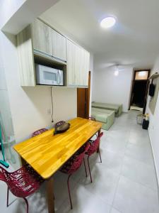 a kitchen with a wooden table and red chairs at Apartamento em Ubatuba - Condomínio Ville II - 300 metros da Praia do Sapê - Maranduba in Ubatuba