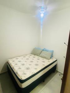a small bed in a room with a light on it at Apartamento em Ubatuba - Condomínio Ville II - 300 metros da Praia do Sapê - Maranduba in Ubatuba