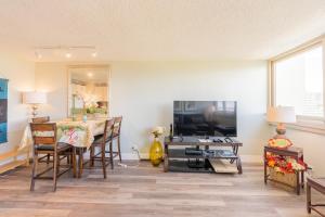 sala de estar con mesa y TV en Island Colony 2301 condo, en Honolulu