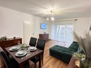ein Wohnzimmer mit einem Tisch und einem grünen Sofa in der Unterkunft Cozy Apartments at Maurer Residence Brasov in Braşov