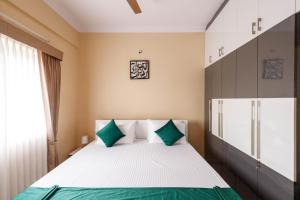 a bedroom with a bed with green and white pillows at Elite Peak Serviced Apartments in Bangalore