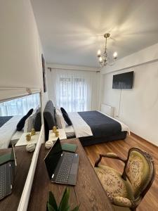 Schlafzimmer mit einem Bett und einem Laptop auf einem Tisch in der Unterkunft Cozy Apartments at Maurer Residence Brasov in Braşov