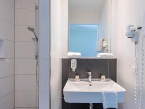 a bathroom with a white sink and a shower at B&B Hotel München-Trudering in Munich