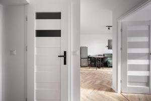 een witte kamer met een deur naar een eetkamer bij Służew 405B Apartment by BookingHost in Warschau +15 foto's
