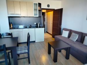 ein Wohnzimmer mit Couch und Tisch und eine Küche in der Unterkunft Alpine Lodge Bansko Apartments in Bansko