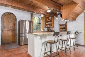 eine Küche mit einer Bar mit Hockern und einem Kühlschrank in der Unterkunft Le Chateau de Laurelwood in Eugene