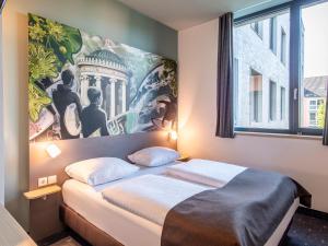 1 dormitorio con 1 cama y una gran pintura en la pared en B&B Hotel München-Trudering, en Múnich