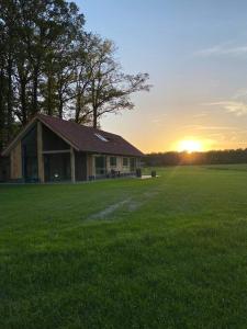Ein Haus auf einem Feld mit Sonnenuntergang im Hintergrund in der Unterkunft Het Haerman in De Lutte