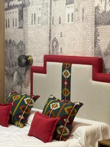 uma cama com cabeceira e almofadas vermelhas e brancas em Posada de los Venerables em Sevilha