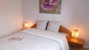 a bedroom with a bed with two lamps and a flower painting at Confortable appartement aux portes de Vannes in Plescop