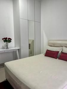 a white bedroom with a bed with a red pillow at Al Mansor Islamic Guestroom in Seremban