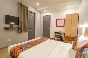 a bedroom with a bed and a desk and a television at FabHotel Golden World in Ghaziabad