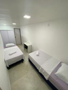 a small room with two beds and a mirror at Pousada Terra Bela in Juazeiro do Norte