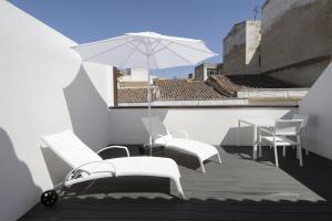 a balcony with a table and chairs and an umbrella at Hostal Emeritae in Mérida