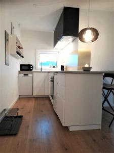cocina con armarios blancos, mesa y ventana en Nordic style apartment in central Aalborg en Aalborg