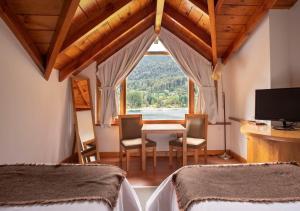 a bedroom with two beds and a table and a window at El Muelle by DOT Boutique in Villa La Angostura