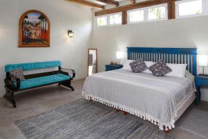 1 dormitorio con cama, banco y ventanas en Casas Palmar and Tocayo, en Sayulita