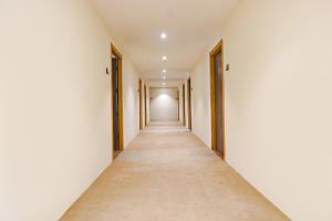 an empty corridor with white walls and a long hallway at FabHotel Dreams Inn in Pune