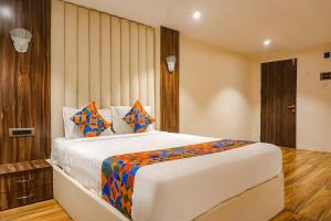 a bedroom with a large white bed with colorful pillows at FabHotel Dreams Inn in Pune