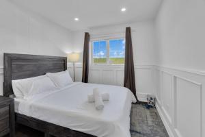 Luxury 3BR - 10 Min to Wonderland - Monthly Rental في فوغان: غرفة نوم بسرير ابيض عليها منشفتين