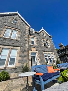 a blue bench in front of a stone house at Barriemore Oban in Oban