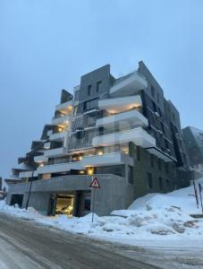 a building on the side of a snow covered street at Apartman Olaf Bjelašnica in Bjelašnica