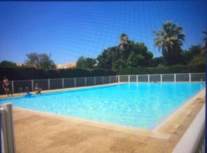 a large swimming pool with blue water at STUDIO REFAIT À NEUF BORD DE MER in Six-Fours-les-Plages