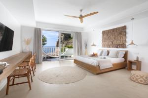 a bedroom with a bed and a desk and a balcony at Maya Beach Resort in Massa Lubrense