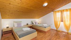 a bedroom with two beds and a wooden ceiling at Charming stone Villa Carla near the sea and town by WiiBuk in Pula +29 photos