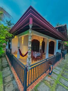 a house with a large porch with a fence at Kawshan Home Stay in Hiriketiya