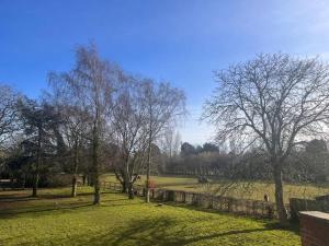 a park with trees and a stone wall and grass at The Paddocks in Moulton Chapel