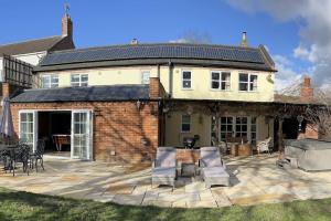 a house with a patio with chairs and a grill at The Paddocks in Moulton Chapel