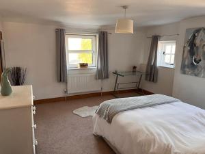 a bedroom with a white bed and two windows at The Paddocks in Moulton Chapel