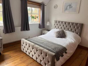 a bedroom with a bed with a tufted headboard and a window at The Paddocks in Moulton Chapel