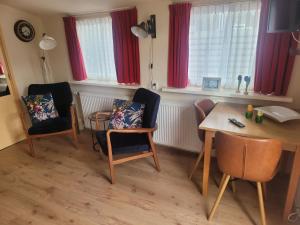 una sala de estar con mesa, sillas, mesa y un taburete en Appartement Canberra., en Bergen aan Zee
