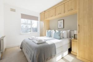 a bedroom with a large white bed with blue pillows at The Wembley Collection in London