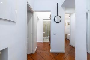 a hallway with white walls and a mirror and a tile floor at Colosseo 85 in Rome