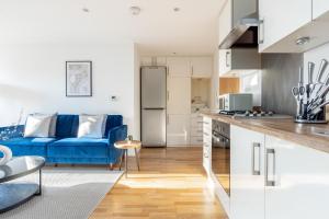una cucina e un soggiorno con divano blu di The Wembley Collection a Londra