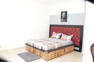 a bedroom with a bed with a red headboard at KRISTAL HOME in Yaoundé