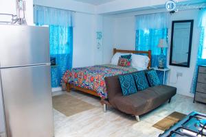 a blue bedroom with a bed and a refrigerator at PRI Studio Apartment in Arnos Vale