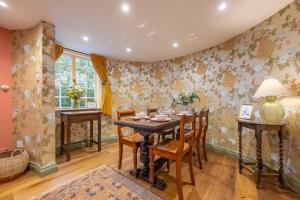 a dining room with a table with chairs and floral wallpaper at A fairy-tale luxurious cottage - The Tea Caddy in Colchester