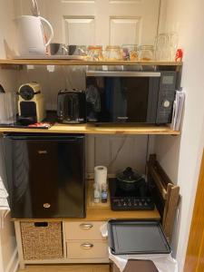 a microwave sitting on top of a shelf at ‘The Den’ Self contained one bedroom annexe. in Stockbridge