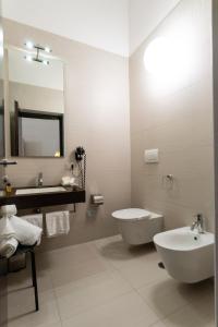 ein Badezimmer mit einem Waschbecken, einem WC und einem Spiegel in der Unterkunft Palazzo Indelli in Monopoli