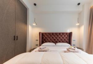 a bedroom with a large white bed with a brown headboard at Nicolas Centrale-Smart City Suites in Igoumenitsa