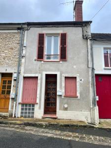un edificio con puertas rojas y ventanas en una calle en Escapade Moretaine - L'Echappée au charme d'antan, en Moret-sur-Loing