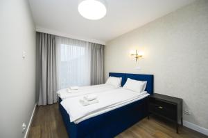 ein Schlafzimmer mit einem blauen Bett mit weißer Bettwäsche und einem Fenster in der Unterkunft Sunrise - Letnica by OneApartments in Danzig