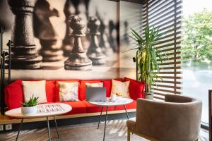 a living room with a red couch and a table with a laptop at ibis Genève Centre Nations in Geneva