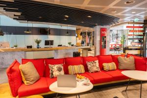 a red couch in a store with a laptop on it at ibis Genève Centre Nations in Geneva