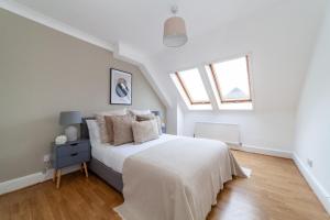 a white bedroom with a bed and two windows at The Lewisham Flats in London